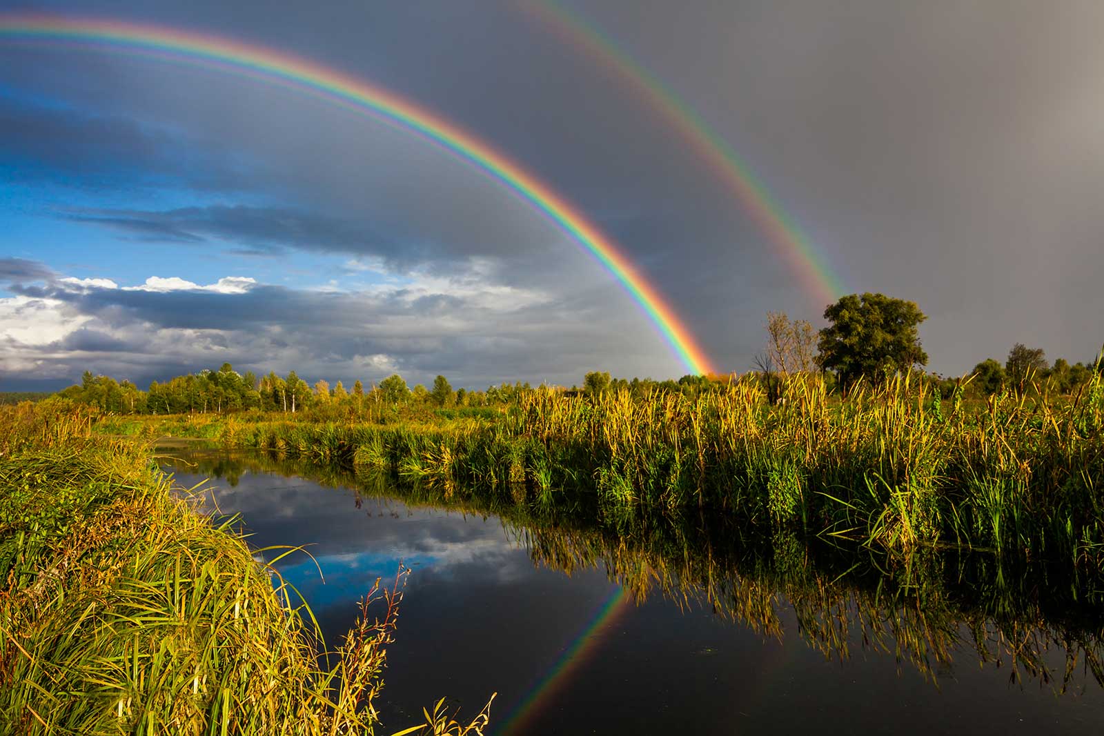 Dubbele regenboog boven een rustige rivier, symbool voor hoop en herstel na een crisis